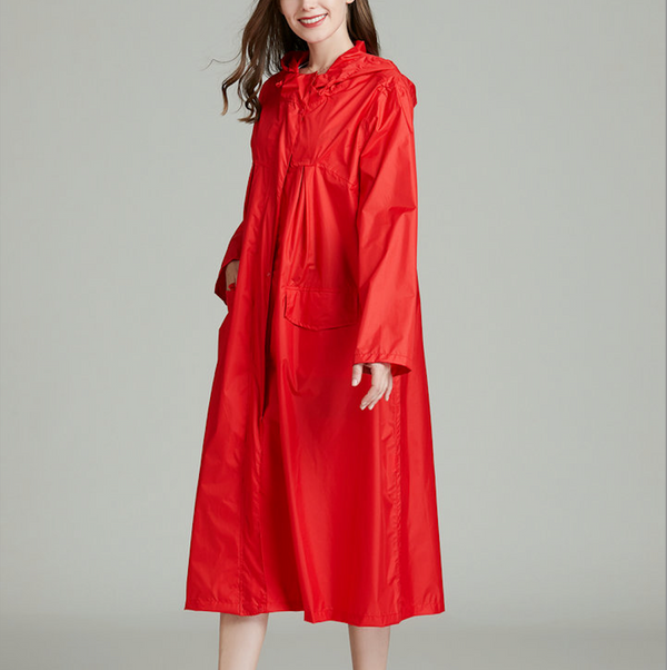 Une femme pose devant un fond gris. Elle porte un rouge à lèvres rouge et un manteau imperméable long rouge. 