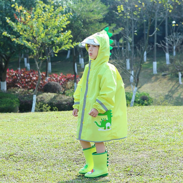 Un garçon pose dans un jardin dans une veste imperméable longue dinosaure verte. 