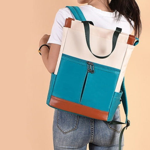 Une femme pose devant un fond orange. Elle porte un tee-shirt blanc un jean et un sac à dos imperméable et étanche avec des patchs de différentes couleurs (blanc, bleu et rouge.)