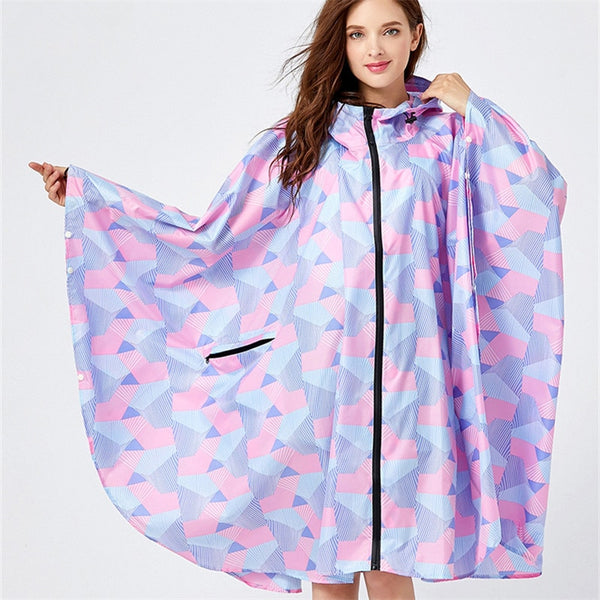 Une femme brune aux yeux bleus porte une veste imperméable poncho à motif géométrique pastel rose.