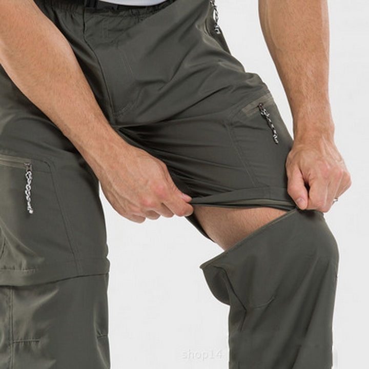 Un homme pose en pantalon léger de randonnée imperméable kaki. Il est en train d'ouvrir une fermeture au niveau du genou pour le transformer en short.